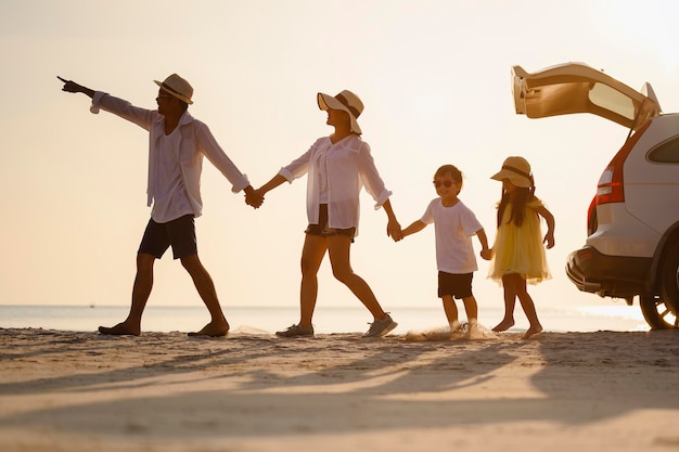 Famille, voyage, plage, détente, style de vie, concept de vacances. Famille qui aime un pique-nique. Les parents tiennent leurs enfants par la main et marchent sur la plage au coucher du soleil en vacances.