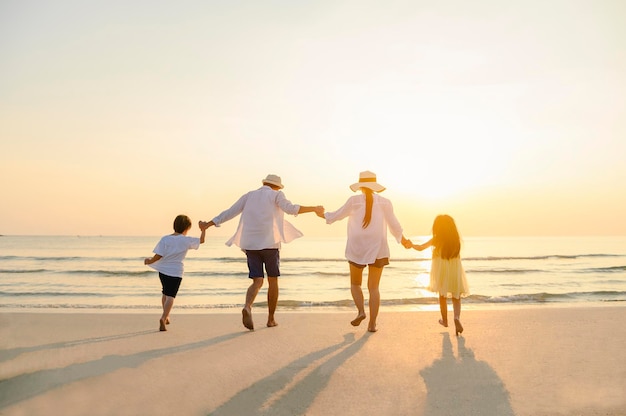 Famille, voyage, plage, détente, style de vie, concept de vacances. Famille qui aime un pique-nique. Les parents tiennent leurs enfants par la main et marchent sur la plage au coucher du soleil en vacances.