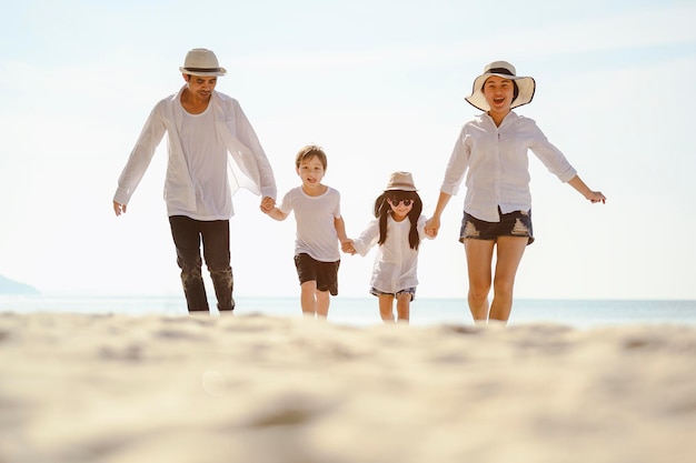 Famille, voyage, plage, détente, style de vie, concept de vacances. Famille qui aime un pique-nique. Les parents tiennent leurs enfants par la main et marchent sur la plage au coucher du soleil en vacances.