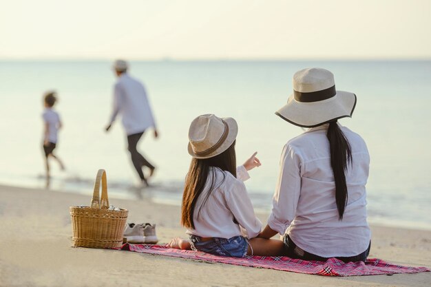 Famille, voyage, plage, détente, style de vie, concept de vacances. Parents et enfants qui pique-niquent à la plage au coucher du soleil en vacances.