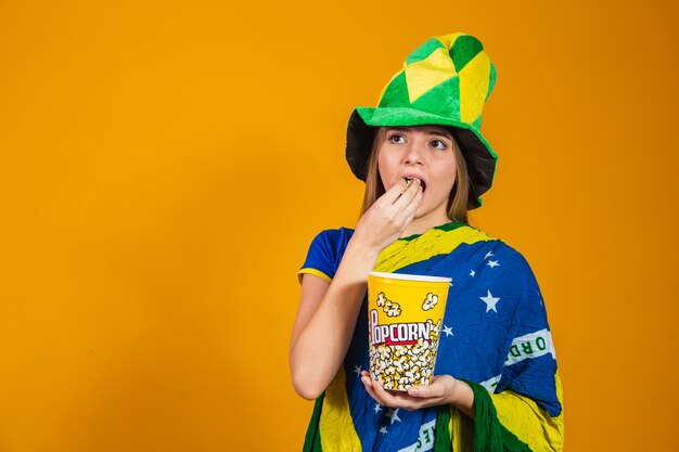 Fan brésilien avec du pop-corn pour regarder le match. concept de divertissement et de sport