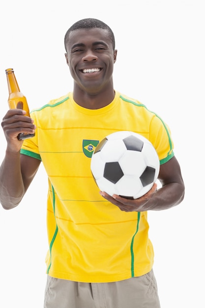 Fan de football brésilien heureux en tenant la bière et le ballon jaune