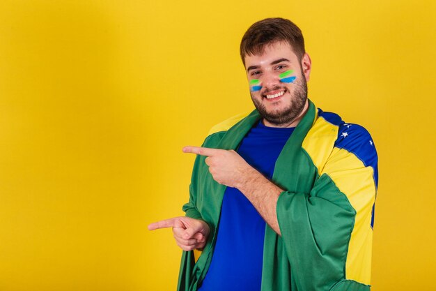 Fan de football brésilien homme caucasien du brésil pointant avec les doigts vers la photo de gauche pour l'annonce