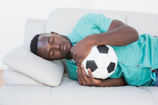 Fan de football étreindre la balle sur le canapé