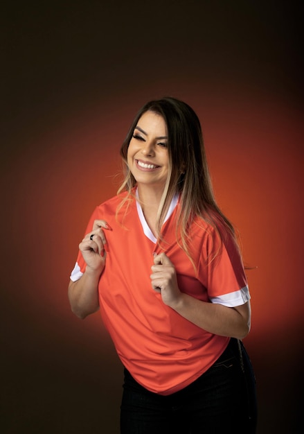 Fan de football femme acclamant son club préféré et l'équipe de coupe du monde fond orange