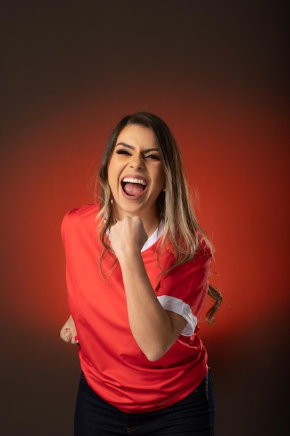 Fan de football femme acclamant son club préféré et fond rouge de coupe du monde d'équipe