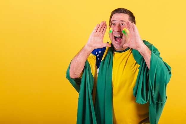 Fan de football homme adulte du brésil à l'aide d'un drapeau criant une photo publicitaire de promotion