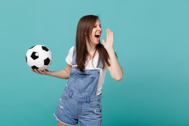 Fan De Football De Jeune Fille Folle égayer L'équipe Préférée De Soutien Avec Un Ballon De Football Criant Avec Un Geste De La Main Isolé Sur Fond Bleu Turquoise En Studio. Les émotions Des Gens Sport Concept De Loisirs En Famille.