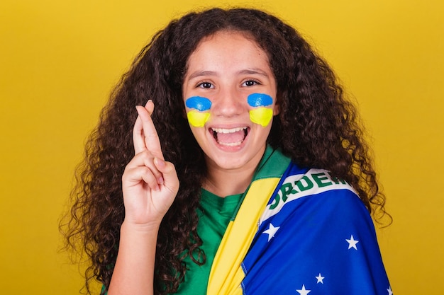 Fan de football de race blanche brésilienne fille doigts croisés acclamations souhaitant plein d'espoir