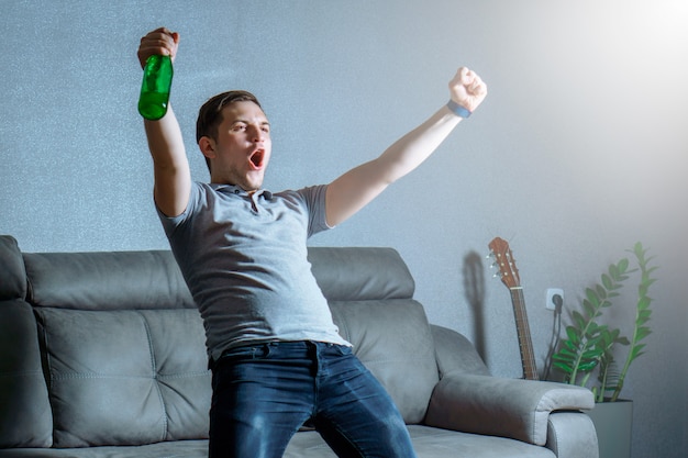 Fan de football regardant la télévision dans un entraîneur avec de la bière et criant BUT