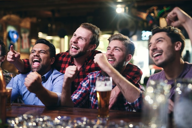 Fans de football enthousiastes regardant le football dans le pub