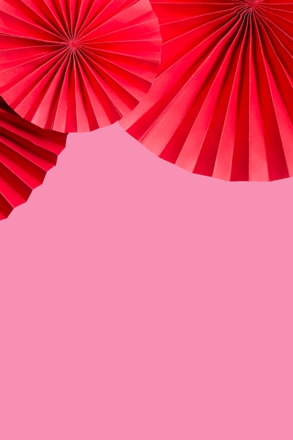 Photo fans de papier rouge sur fond rose copie espace format vertical