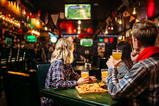 Fans regardant match et boit de la bière au bar des sports