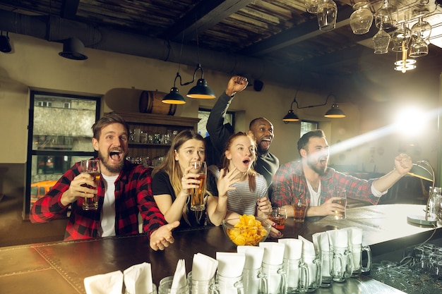 Les fans de sport applaudissent au bar-pub et boivent de la bière pendant la compétition de championnat