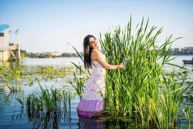 Fantastique jolie femme debout près des carex dans l'eau