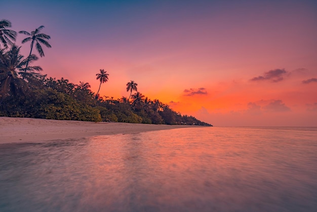 Fantastique vue rapprochée des vagues d'eau de mer calme avec la lumière du soleil orange au coucher du soleil. Île tropicale