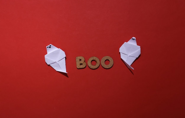 Fantômes de papier et le mot BOO sur fond rouge. Thème Halloween