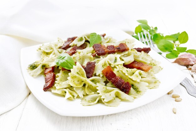 Photo farfalle au pesto et bacon dans une assiette sur tableau blanc