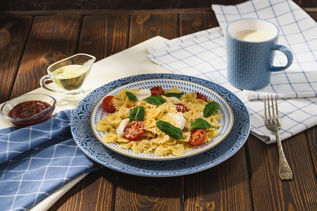 Farfalle aux tomates cerises mozzarella et épinards dans un style rustique.