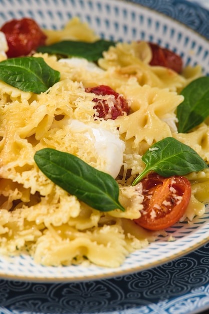 Farfalle aux tomates cerises mozzarella et épinards dans un style rustique.