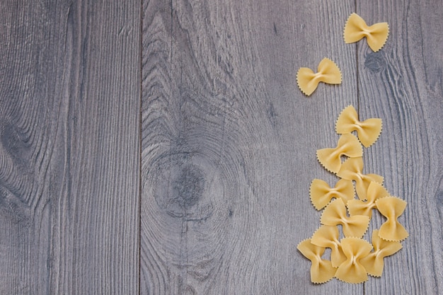 Farfalle italienne de pâtes crues italiennes non cuites sur fond en bois rustique.