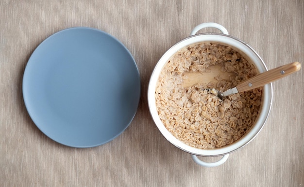 Farine d'avoine dans une casserole avec assiette vide Petit-déjeuner à l'avoine le matin