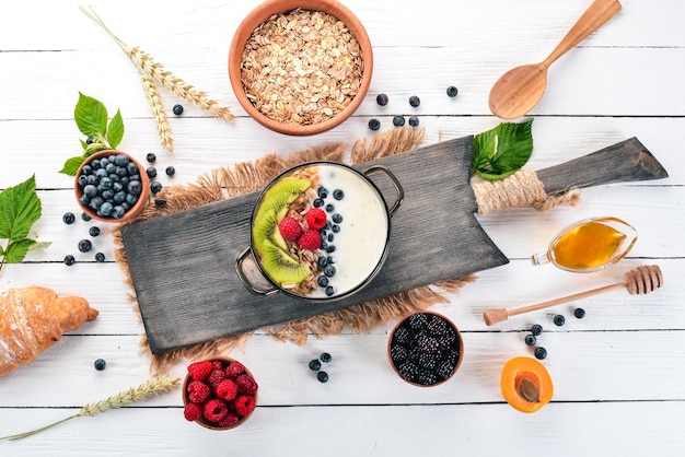 Farine d'avoine avec yaourt et fruits et baies Kiwi myrtille framboise Sur un fond en bois Vue de dessus Espace libre pour le texte