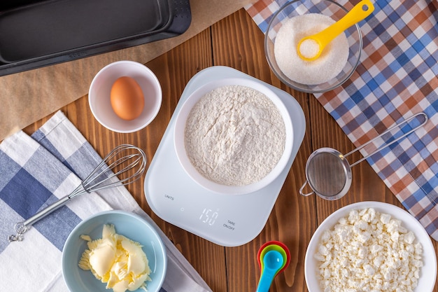 Farine sur balance de cuisine numérique avec ingrédients de biscuits pour la cuisson sur table en bois, poids 150 g.