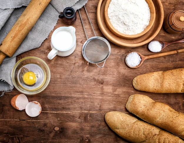 Farine de blé blanche dans un bol en bois et baguettes au four