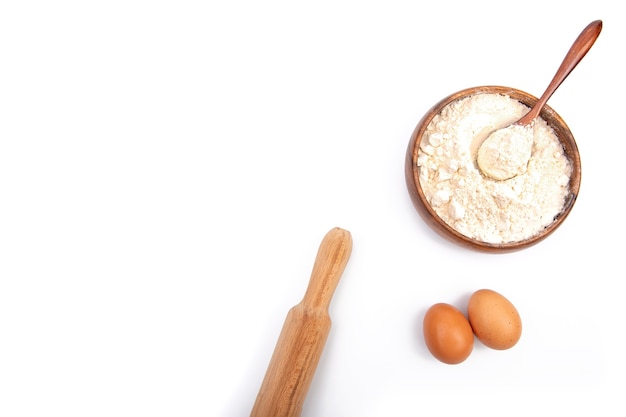 Farine de blé dans un bol en bois et œufs de poule