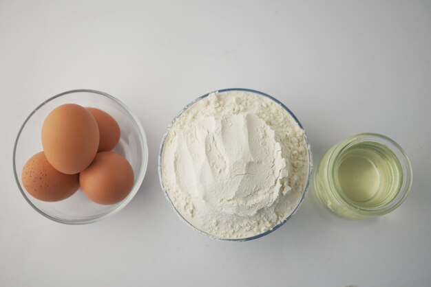 Farine de blé dans un bol oeufs et huile sur table