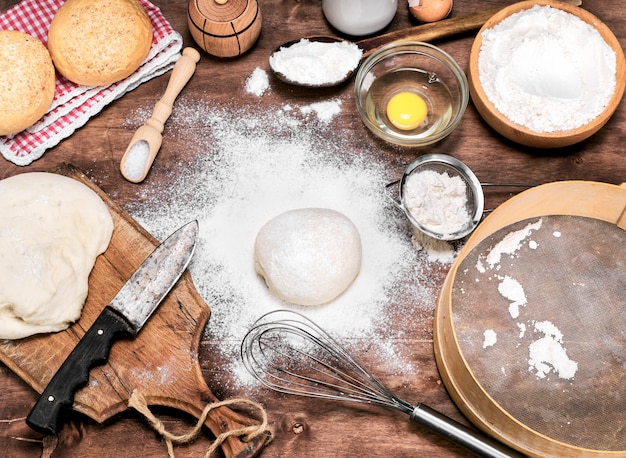 Farine de blé épars sur la table, à côté de la pâte à levure crue