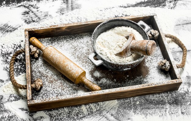 Photo farine dans un bol avec rouleau à pâtisserie dans une boîte en bois sur la table en pierre