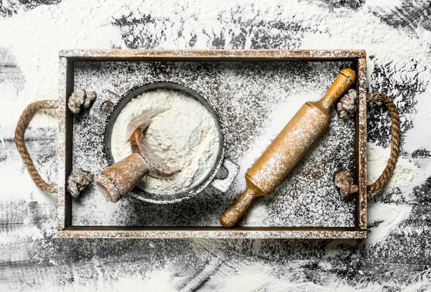 Farine dans un bol avec rouleau à pâtisserie dans une boîte en bois sur la table en pierre