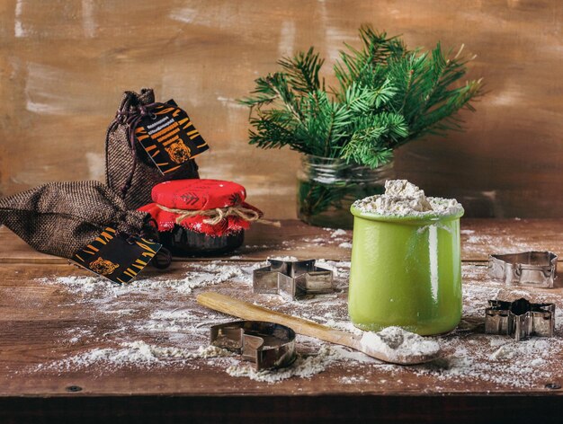 Photo farine d'emporte-pièces de noël dans une boîte en argile et ingrédients pour biscuits dans des sacs en toile de jute