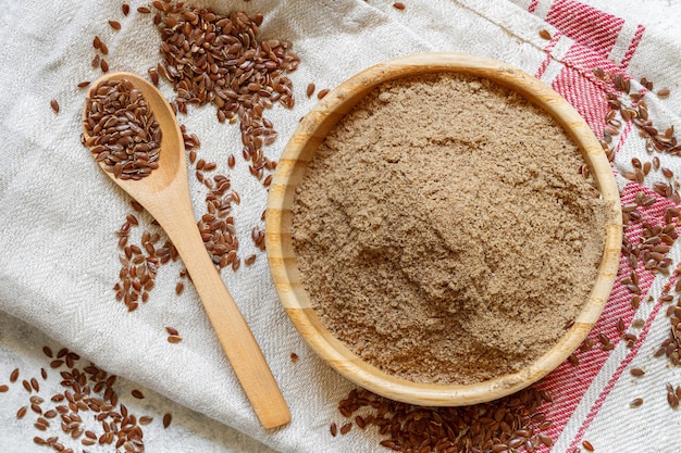 Farine de graines de lin crues dans un bol en bois avec une cuillère vue de dessus