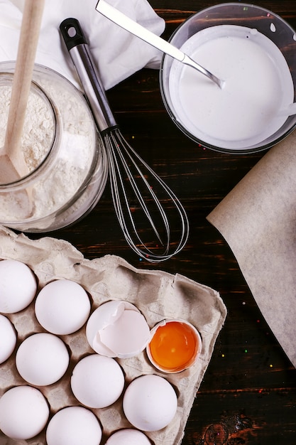 Farine, oeufs de kéfir et un fouet sur une table en bois. Préparer le mélange pour les crêpes, cuisiner.