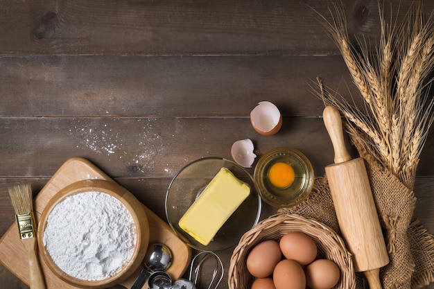 Farine à pain avec œuf frais, beurre non salé et boulangerie d'accessoires sur une surface en bois, préparez-vous pour le concept de boulangerie maison