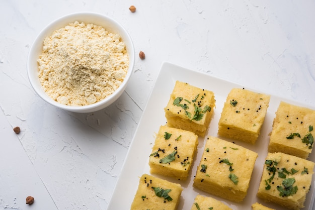 Farine de pois chiches ou poudre de Besan dans un bol en céramique ou en bois avec une collation Gujrati Dhokla