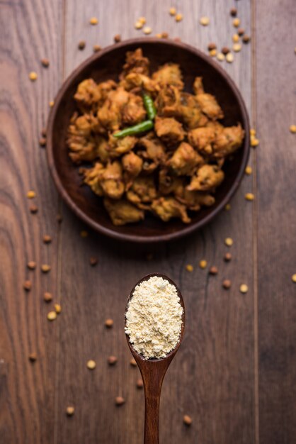 Farine de pois chiches ou poudre de Besan dans un bol en céramique ou en bois avec des oignons frits pakora ou kanda bajji