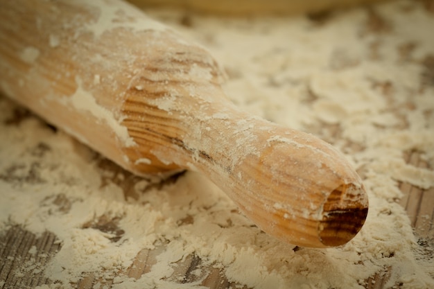 Farine tamisée sur la table et un rouleau à pâtisserie