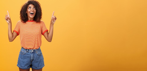 Fasciné impressionné et amusé charmante femme afro-américaine avec une coiffure afro en tr