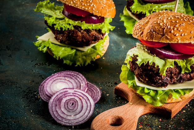 Fast food. Aliments malsains. Délicieux hamburgers frais et savoureux avec escalope de boeuf, légumes frais et fromage sur béton bleu foncé. fond