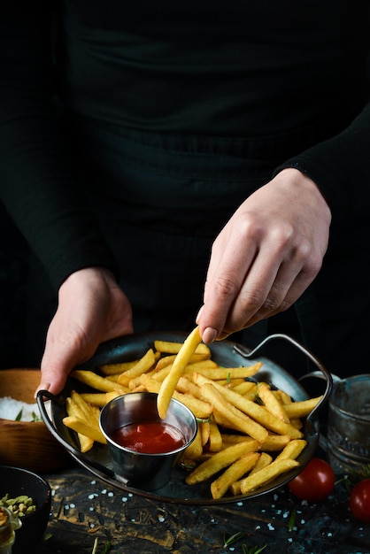 Fast food. Frites avec sauce sur une plaque de métal, sur fond de bois rustique. Notion de restauration rapide.