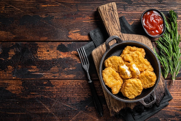 Fastfood - Nuggets frits de poulet dans une casserole. Fond en bois. Vue de dessus. Espace de copie.