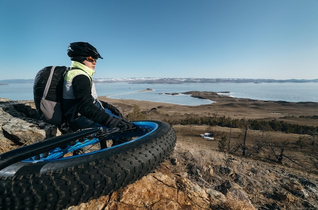 Fatbike (également appelé fat bike ou fat-tire bike) - Cyclisme sur grandes roues. Teen fait du vélo à travers les montagnes enneigées en arrière-plan.