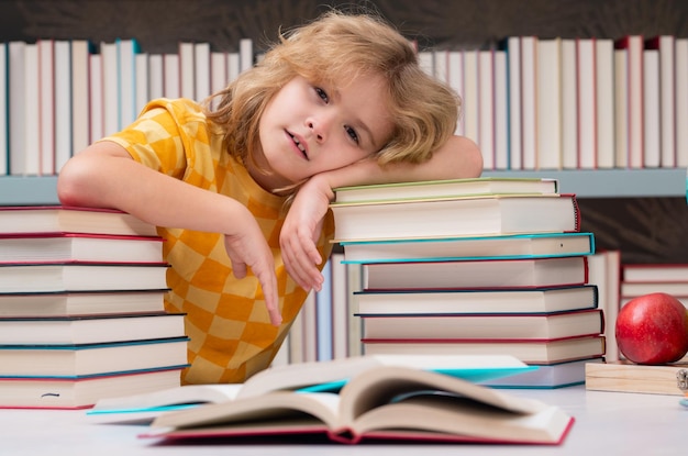 Fatigué de l'écolier s'ennuie à l'élève de l'école enfant n'étudie pas lire le livre en classe de l'enfant de l'école élève rea