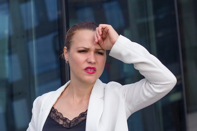 Fatigué, épuisé, jeune femme d'affaires souffrant de maux de tête, désespérée et stressée à cause de la douleur et de la migraine en plein air. La main sur la tête. Travail difficile, stressant, travail, ayant des problèmes. Se sentir malade.