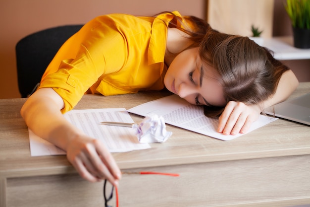 Fatigué femme travaillant sur l'ordinateur portable au bureau