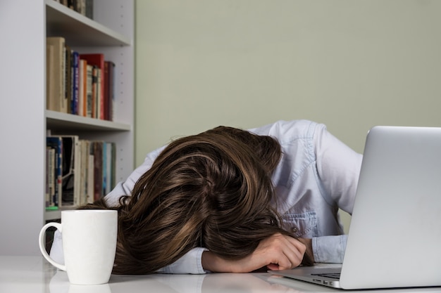 Fatigué fille posant sa tête sur la table de travail avec ordinateur